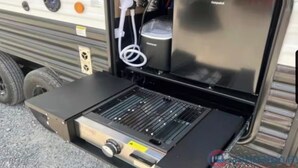 Ein tragbarer Grill mit Bedienfeld, Stromkabel und einem Behälter im Fahrzeuginneren.