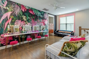 Ein Zimmer mit einem Bett, einem Schminktisch mit Beleuchtung, einer Bar und einem großen tropischen Wandbild.