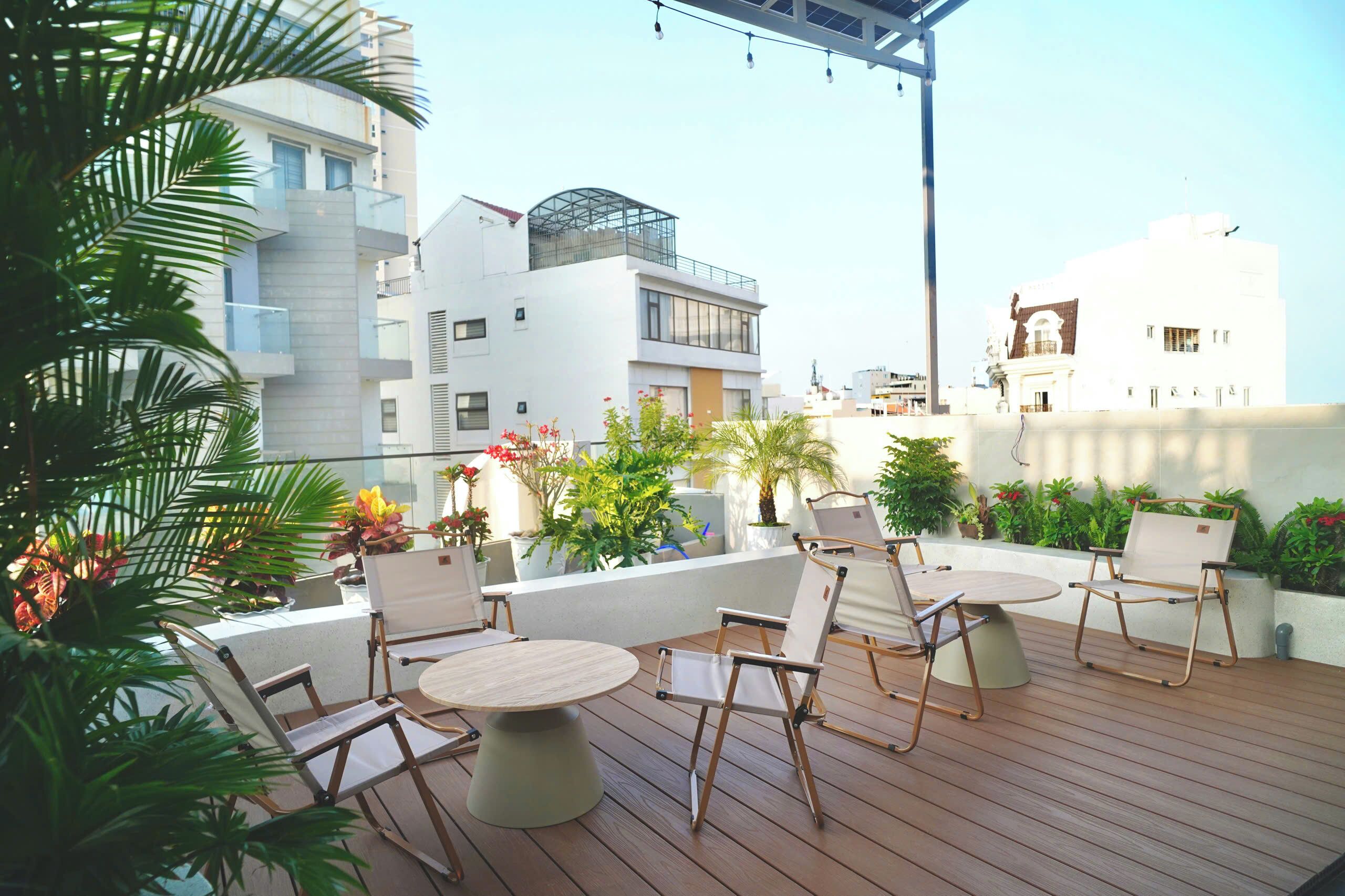 Terraza en la azotea con mobiliario exterior, plantas en macetas y vistas de edificios circundantes.