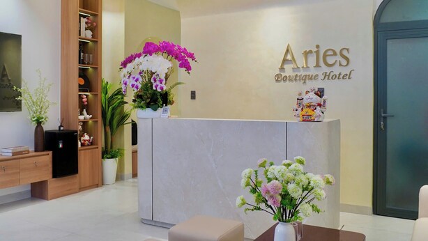 A hotel reception area with a marble counter, a wooden shelving unit, and a wall-mounted sign for 'Aries Boutique Hotel.' - Aries Boutique Hotel Vung Tau (Ho Chi Minh City)