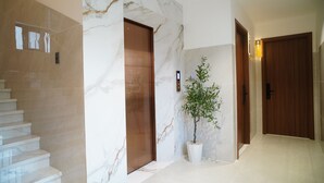 A marble staircase, wooden doors, and a potted plant in a hallway. - Aries Boutique Hotel Vung Tau (Ho Chi Minh City)