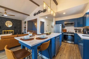 Una cucina moderna con mobili blu, un'isola centrale e un'area pranzo con un divano in pelle marrone.