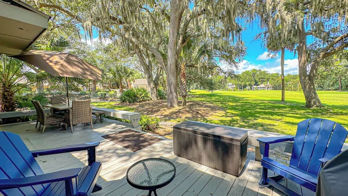 A deck with outdoor furniture, a hot tub, and a view of a grassy area.