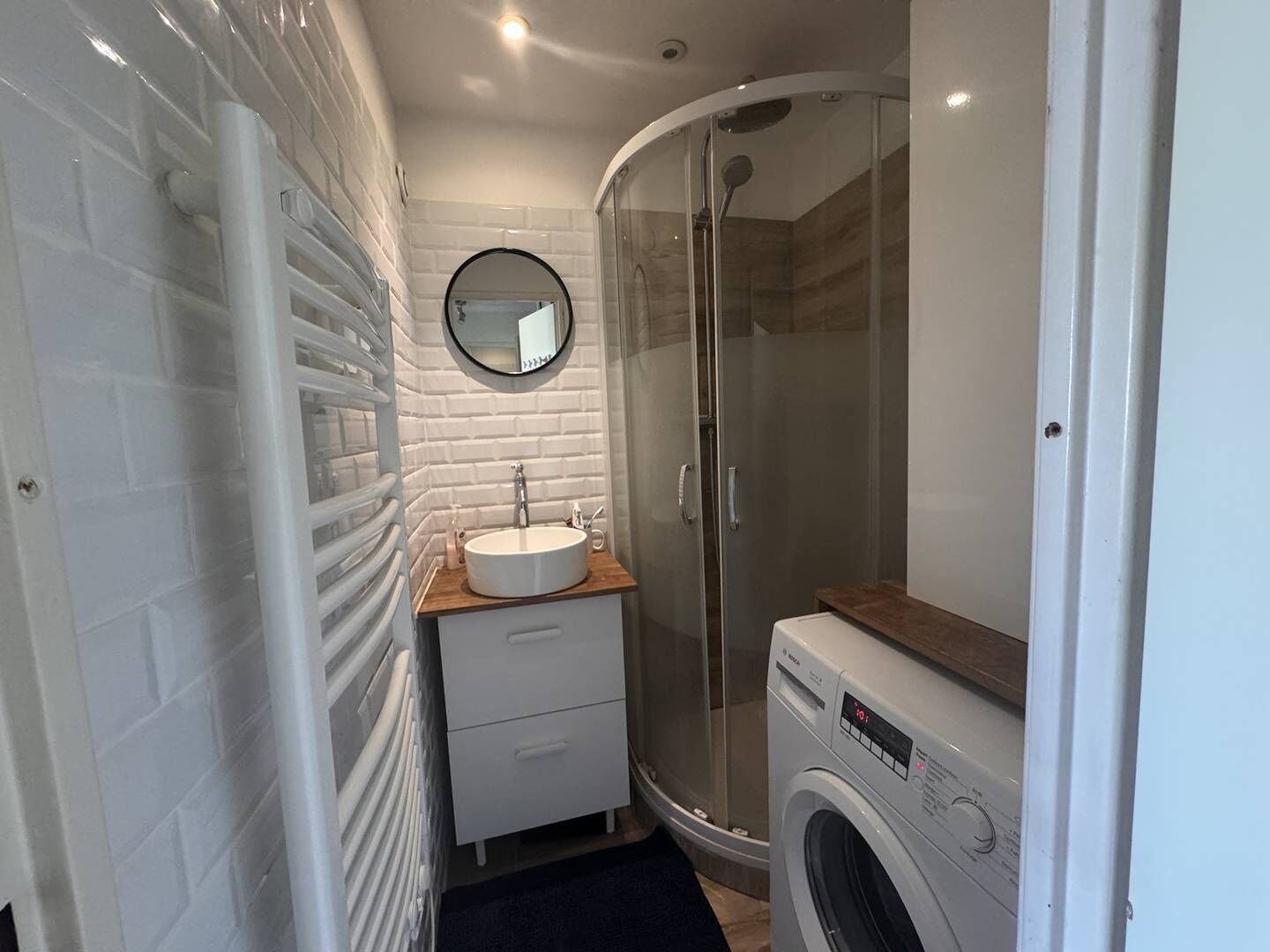 Un bany petit i funcional amb un lavabo, un mirall i plat de dutxa amb portes de vidre.
