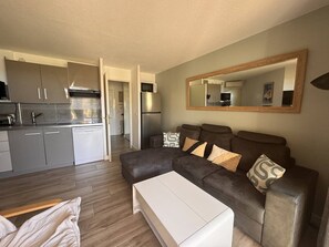 Ein modernes Wohnzimmer mit einer Couch, einem Couchtisch und einer Küche im Hintergrund.