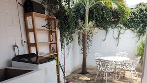 Una cocina con lavadora, un escoba y una mesa con sillas.