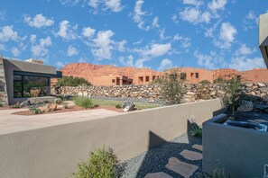 A modern building with a stone facade, a stone wall, and a clear blue sky.