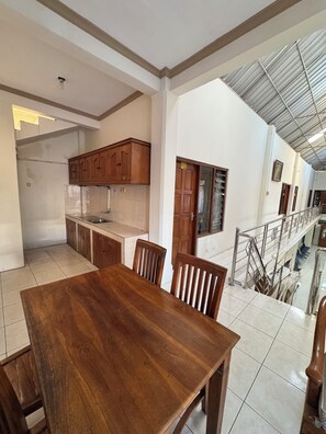 A spacious kitchen with wooden cabinets, a dining table, and chairs. - Griya Helin (Colomadu)