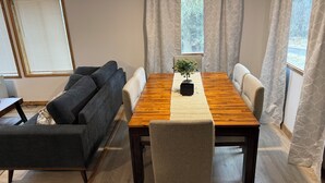 En matplats med ett träbord, två stolar, en liten krukväxt och en grå soffa.