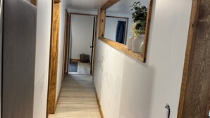 En smal hall med trägolv, en stor spegel på den högra väggen och en dörr på den vänstra.