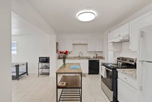 A modern kitchen with white cabinets, a central island, a stove, and a sink. - Tucson Safari 3/1.5, Crib, Zoo, UofA, Golf, DMAFB (Tucson)