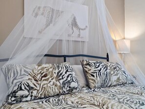 A bed with a zebra-patterned bedspread and pillows, a canopy, and a wall-mounted artwork of a leopard. - Tucson Safari 3/1.5, Crib, Zoo, UofA, Golf, DMAFB (Tucson)