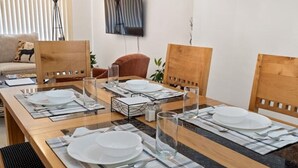 Una mesa de comedor dispuesta con platos, vasos y cubiertos, rodeada de sillas de madera.