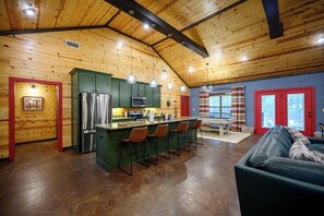 Ein Holzblockhaus-Innenraum mit Küche, Essbereich und Wohnzimmer mit einer Couch.