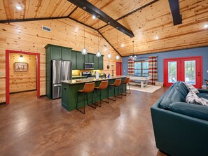A spacious kitchen with a central island, green cabinets, and stainless steel appliances. - Camp Broken Bow - Pickleball, Arcade & Hot Tub · Private Resort for Groups (Broken Bow)