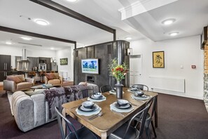 A modern living room with a dining area, a fireplace, and a television. - Chapel on Moray, historical significance with modern luxury. (Dunedin)