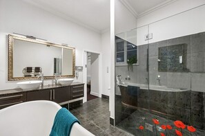 A modern bathroom with a bathtub, two sinks, a large mirror, and a glass-enclosed shower area. - Chapel on Moray, historical significance with modern luxury. (Dunedin)