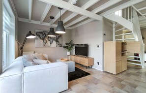 A modern living room with a sofa, a TV, a world map artwork, and a staircase. - Amazing home in Stavenisse with swimming pool (Stavenisse)