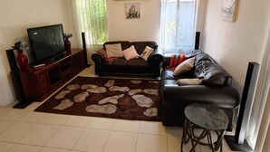 A living room with a sofa, TV, and a decorative rug. - Airport  3-bedroom villa with AC in charming High Wycombe (High Wycombe)