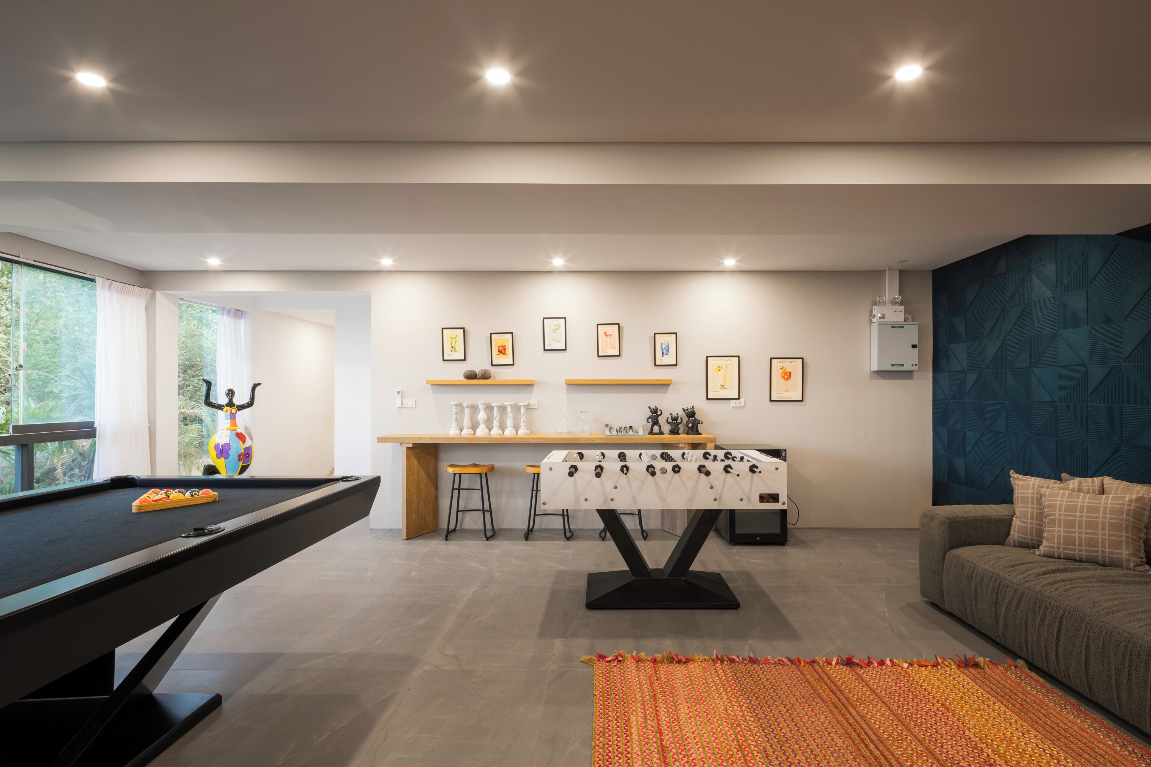 Un salon moderne équipé d’une table de billard, d’un baby-foot et d’un canapé.