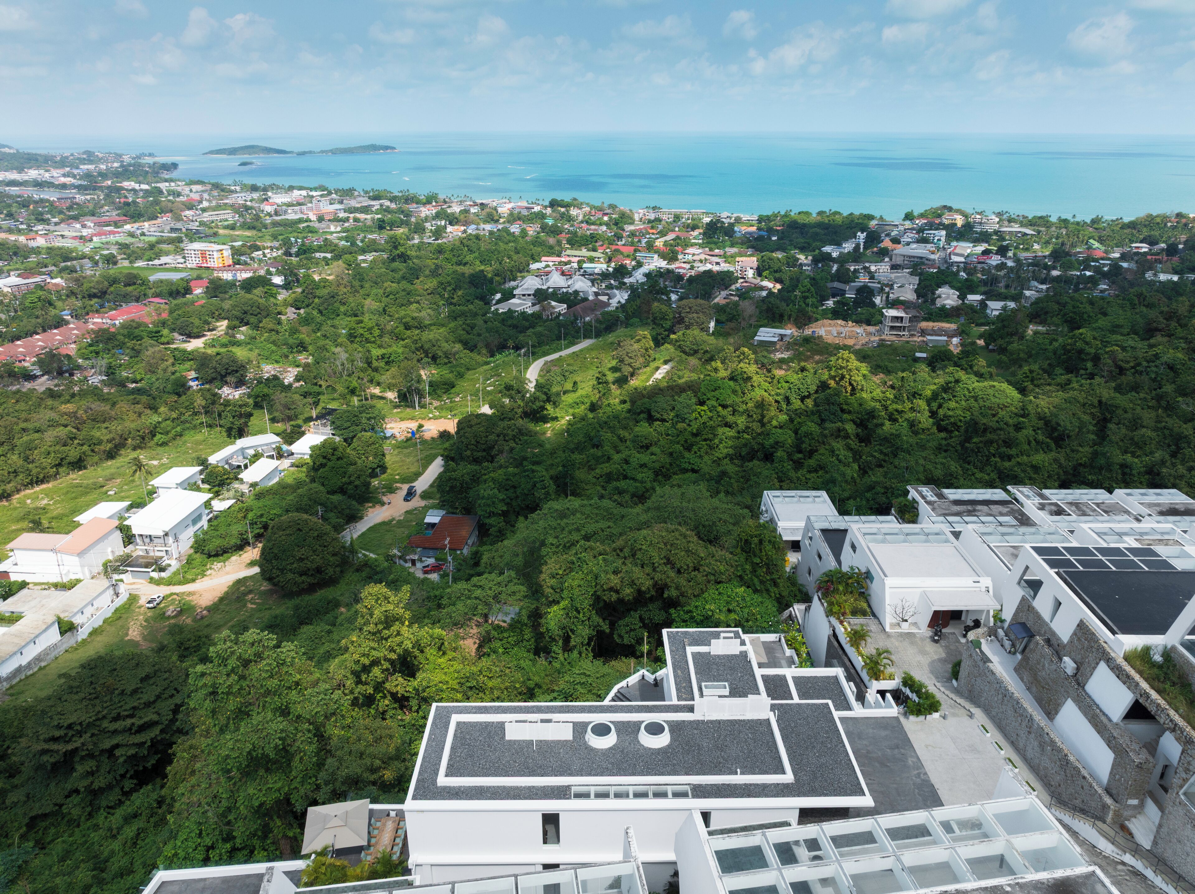 Zona residencial con edificios modernos, vista despejada del océano y un paisaje verde exuberante.