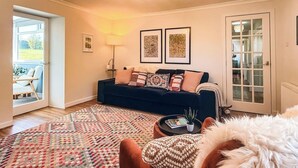 A living room with a sofa, a patterned rug, a lamp, and a door leading to a balcony. - Nether Clashnoir Glenlivet (Ballindalloch)