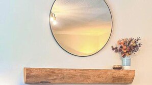 A living room with a fireplace, a round mirror, a wooden shelf, and a small plant on a table. - Nether Clashnoir Glenlivet (Ballindalloch)