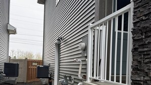 A residential building with a stone facade, a white railing, and a concrete pathway. - Selah’s Suite - (AC+Wifi+3beds(1 King bed +2 twin sofa beds ) (Edmonton)