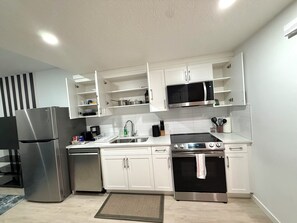 A modern kitchen with white cabinetry, stainless steel appliances, and a tiled backsplash. - Selah’s Suite - Cozy Modern Getaway (Edmonton)
