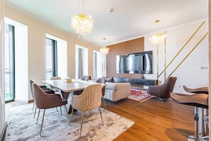Ein modernes Wohnzimmer mit Essbereich, Fernseher und Treppe.