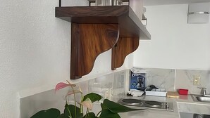 Cozinha com bancada de mármore, uma planta em vaso, bloco de facas e uma caixa em uma prateleira de madeira.