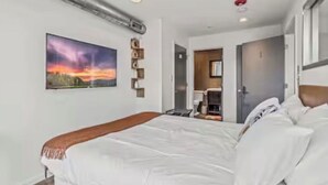 Ett hotellrum med en säng, en tavla, ett skrivbord och en stol.