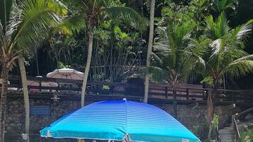 Une plage avec un parasol bleu, des chaises de plage colorées et une glacière sur le sable.