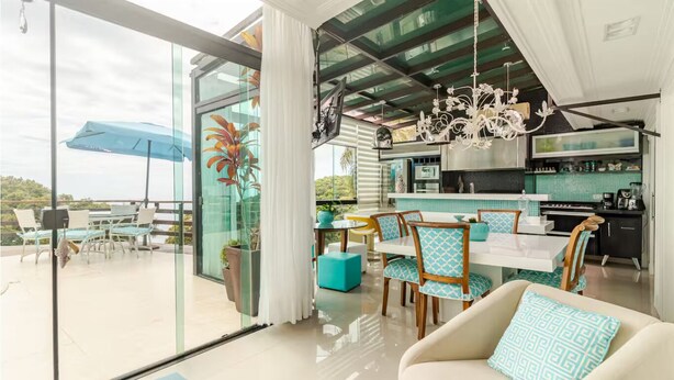 Un interior moderno con comedor, cocina y un amplio ventanal corredera que da a un patio exterior.