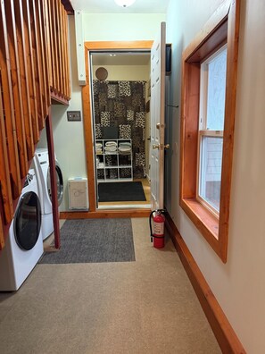 Un cuarto de lavandería con lavadora, extintor y una puerta que da a una habitación con diseño.