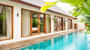 A modern resort with a swimming pool, large windows, and wooden deck. - Villa Toro - Bingin Bali (Pecatu)