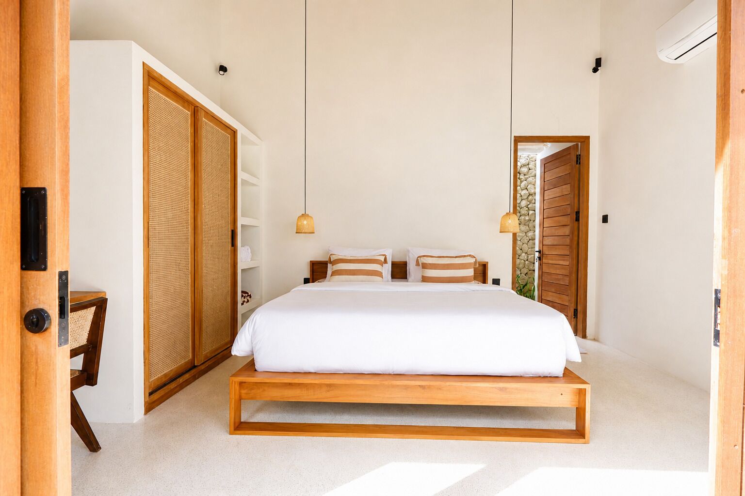A bedroom with a large bed, wooden wardrobe, and a small table.
