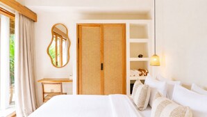 Un dormitorio con una cama, una mesita de noche, un espejo, un armario y una estantería con toallas.