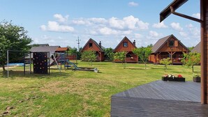 A playground with climbing structures, a wooden deck, and cabins with pitched roofs. - Lovely home in Ko1czewo (Ko1czewo)