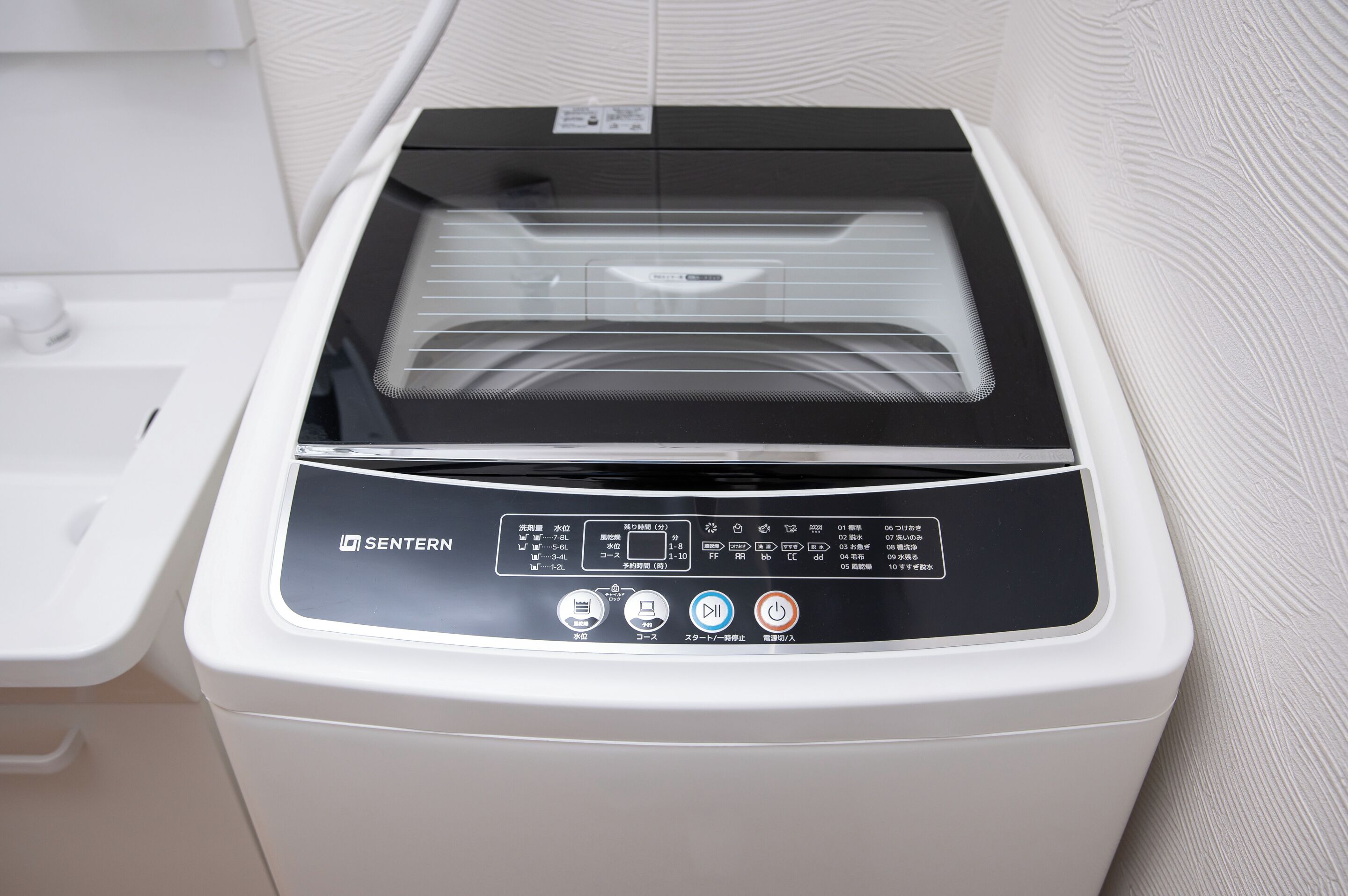 A white and black multifunctional appliance with a control panel, likely a washer and dryer, in a bathroom setting.
