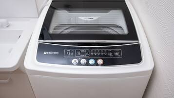 A white and black multifunctional appliance with a control panel, likely a washer and dryer, in a bathroom setting.