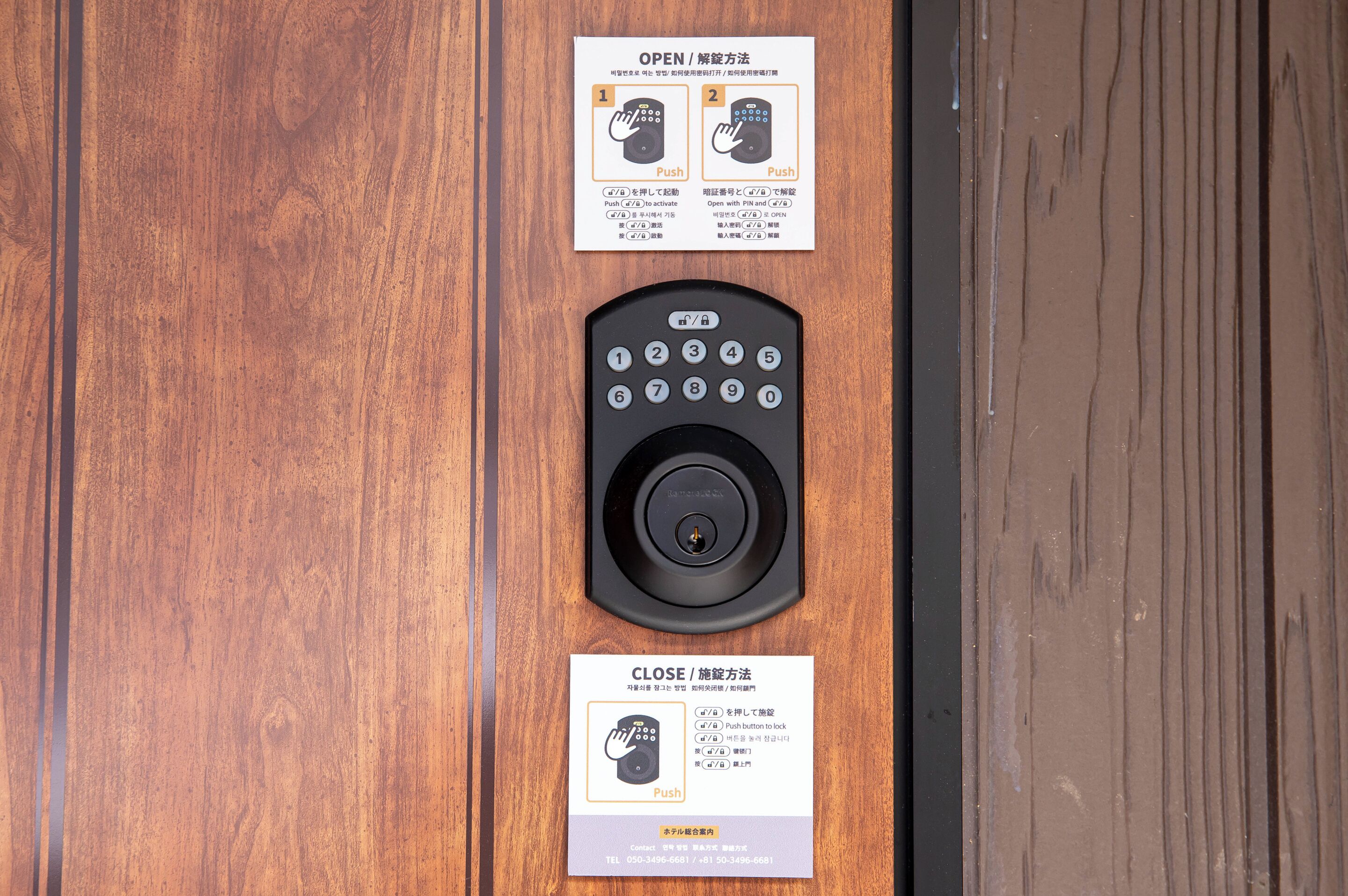 A wooden door with a keypad and two instructional cards for opening and closing the door.