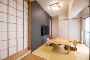 Una habitación tradicional japonesa con suelo de tatami, una mesa baja y un televisor montado en la pared.