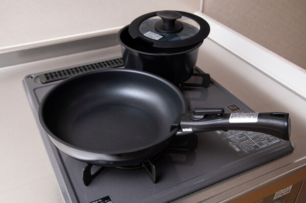 A kitchen with a black frying pan and a pot on a stove.