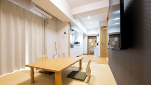 A room with a wooden table, tatami mat flooring, a chair, and a black partition.
