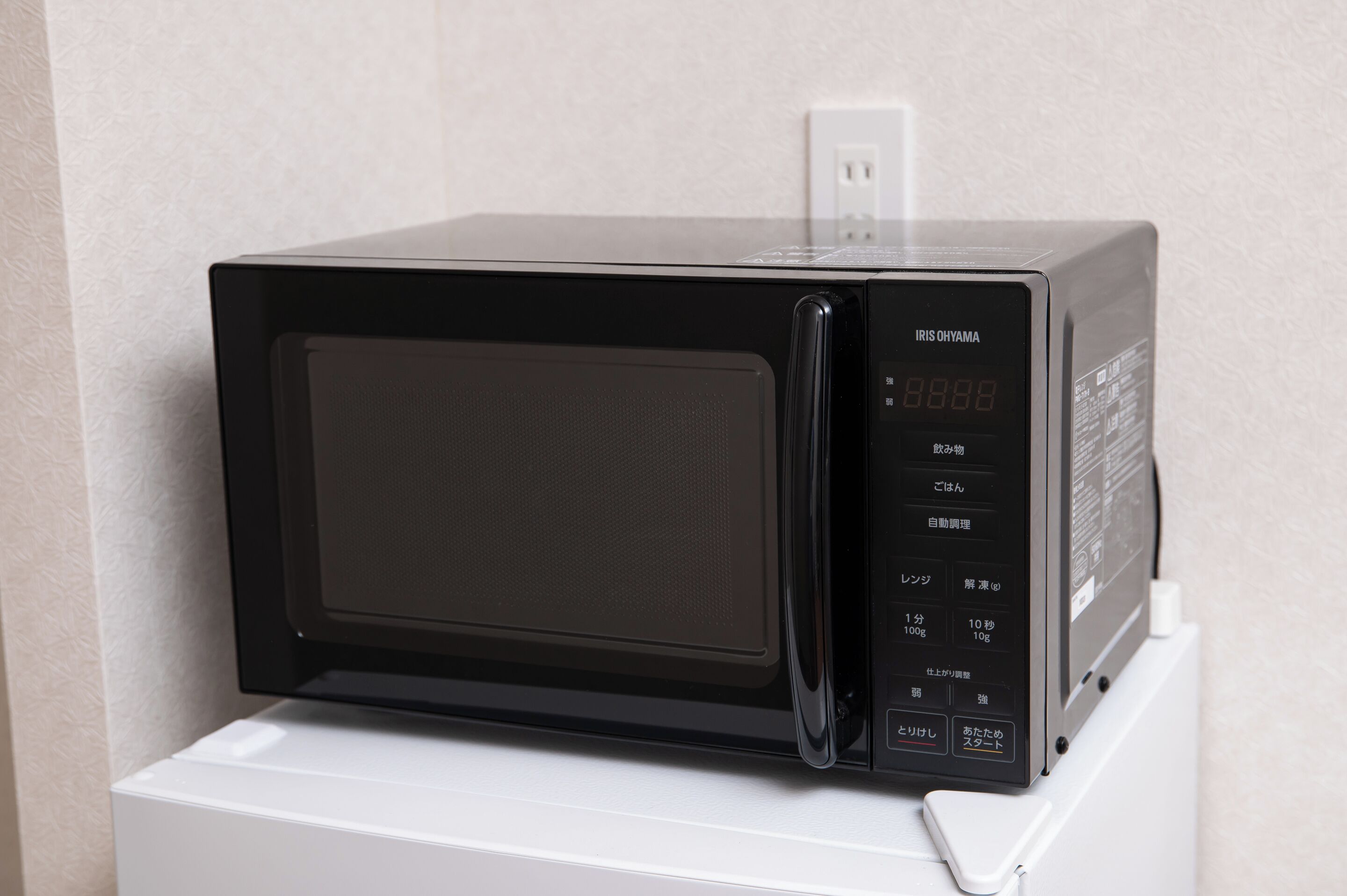 A black microwave on a white appliance base, with a digital display showing '8888'.