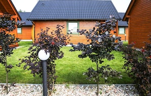 A wooden cabin with a tiled roof, surrounded by a well-maintained lawn and a gravel path. - Lovely home in Rozewie with sauna (Rozewie)