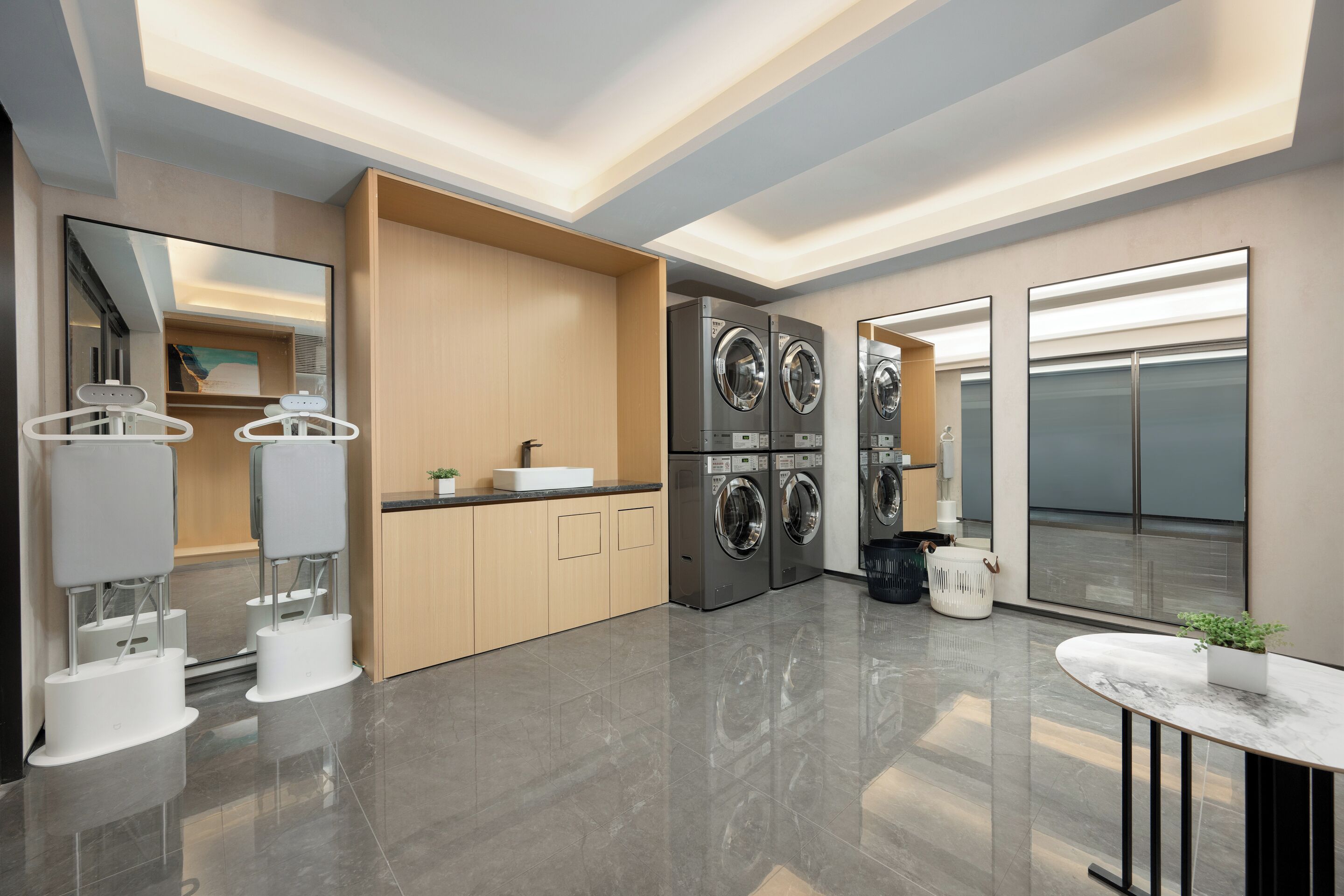 A modern hotel bathroom with a large mirror, a sink, and two washing machines.