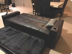 A black leather sofa with a matching ottoman, a small circular table, and a patterned pillow. - Nice Condo 302 in Las Conchas (Las Conchas)