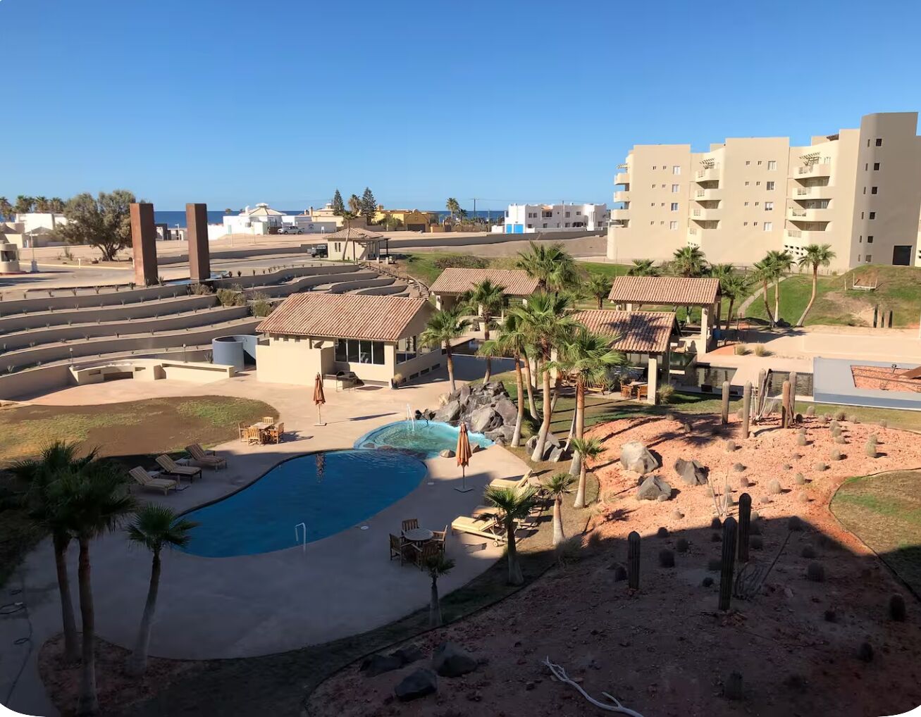 A resort with a swimming pool, palm trees, and a desert landscape.